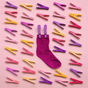Colorful sock with matching clothespins on a pink backdrop, perfect for creative layouts.